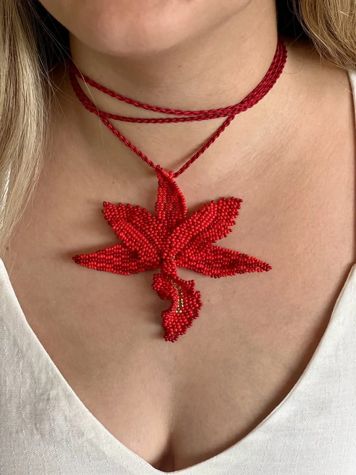 Orquídea roja tejida en mostacilla colgando de un hilo trenzado